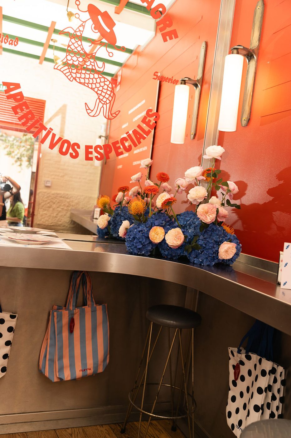 A Hermanos Vinagre bar set up for a brand event, with flowers and hanging bags