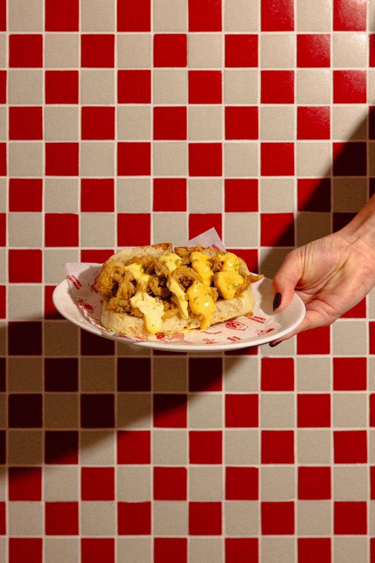 Bocadillo de calamares sobre azulejo rojo y blanco